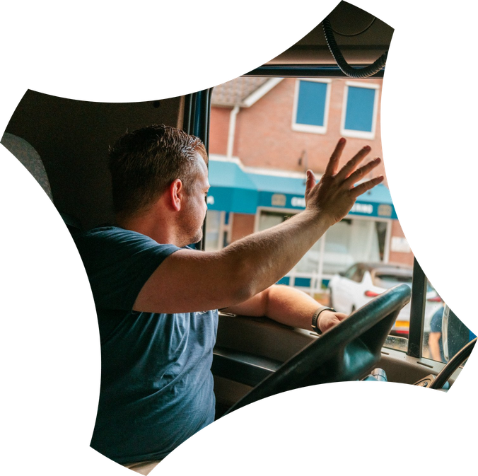 Chauffeur van Kattenberg zwaait vanuit de cabine van zijn vrachtwagen
